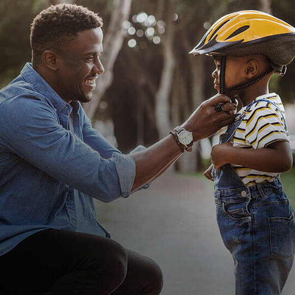 father putting bike helmet on son
